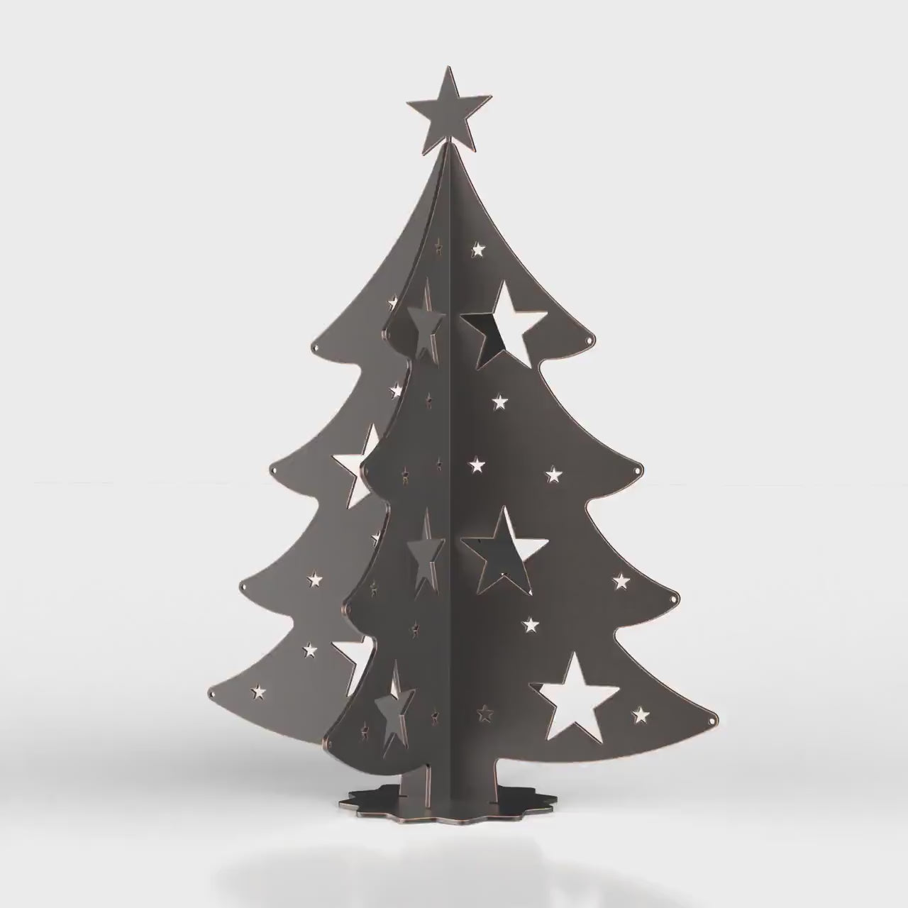 A 3D metal Christmas tree decoration, made from a DXF file, sitting on a table with festive lights in the background.